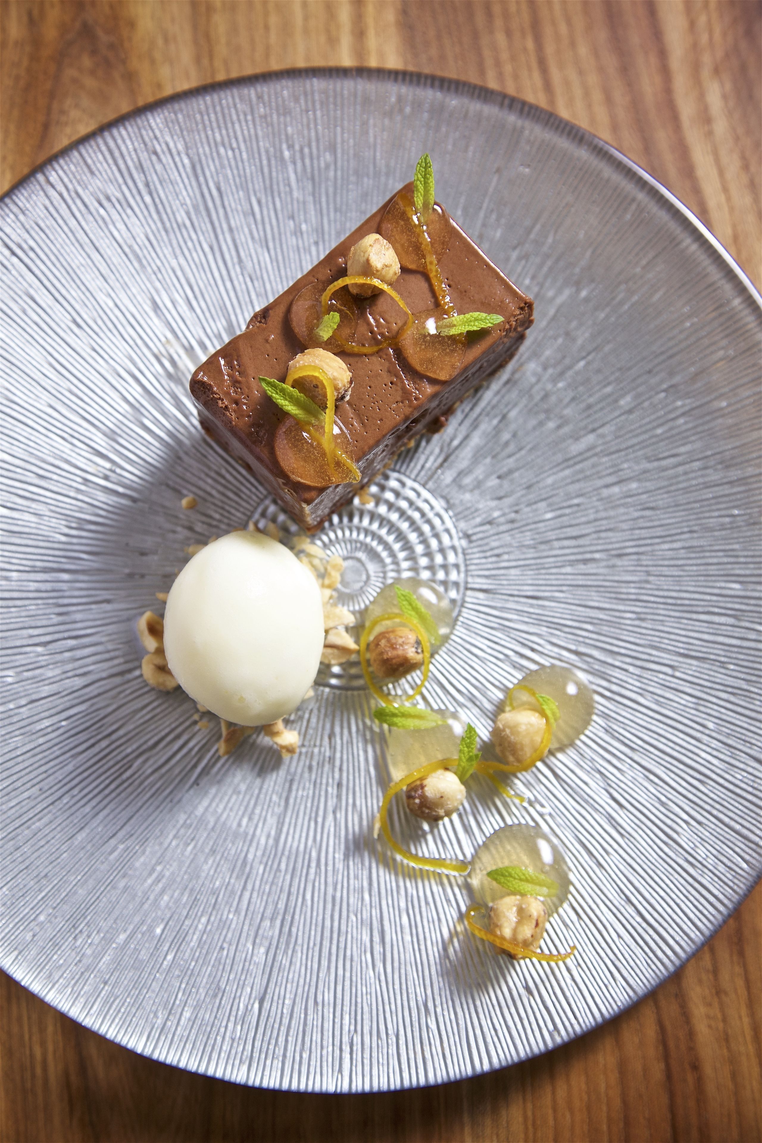 Een dessert op een bord met een structuur, met noten en muntblaadjes.