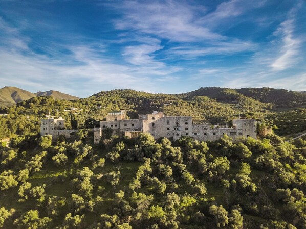 A historic stone castle surrounded by dense forest and hills. - Hotel Castillo de Monda (Monda)
