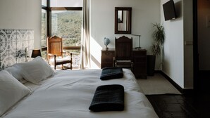 Een slaapkamer met een groot bed, een bureau, een stoel, een wereldbol en een televisie.