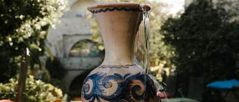 A decorative vase on a gravel surface with a stone building in the background.