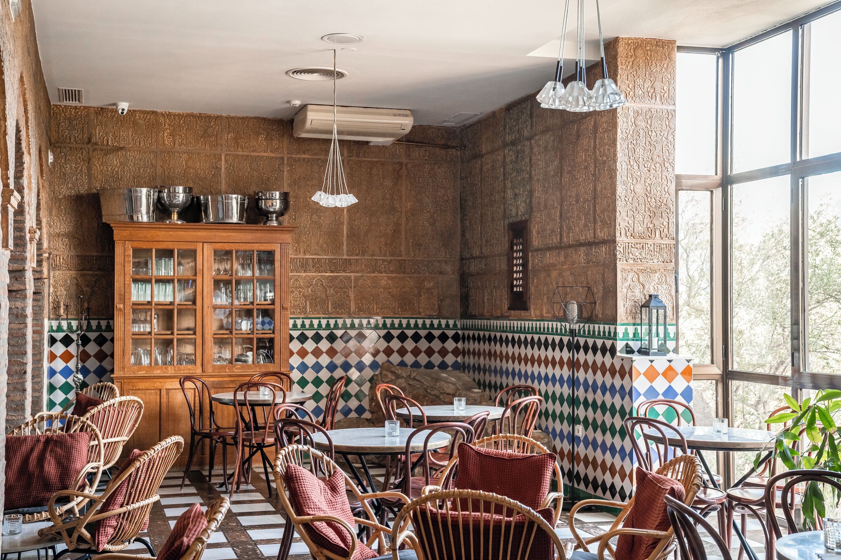 A dining area with wicker chairs, a wooden cabinet with glass doors, and a checkered floor pattern.