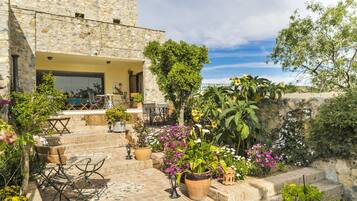 Un edificio de piedra con terraza y plantas en macetas.
