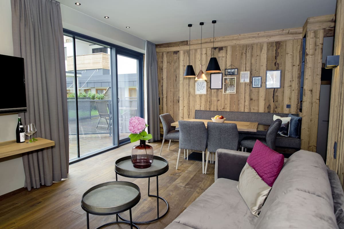 A modern living room with a sofa, a coffee table, and a dining area with a table and chairs.