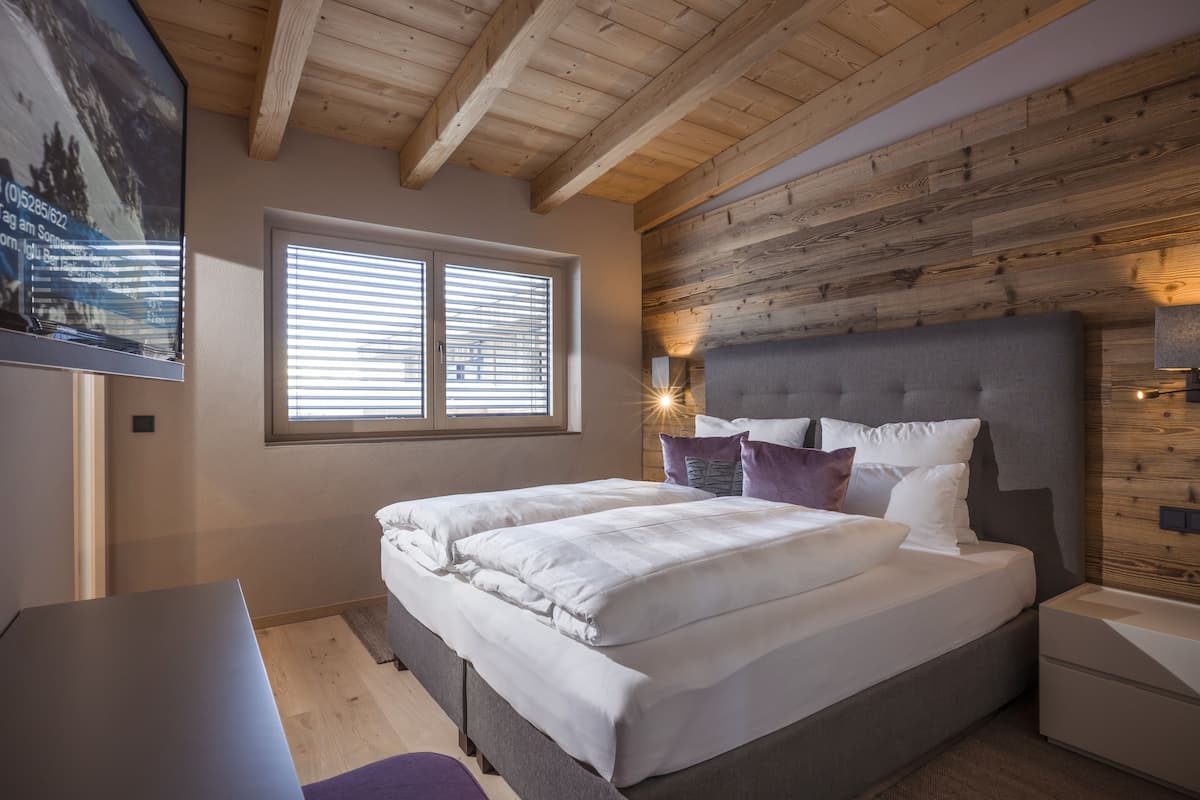 A bedroom with a bed, bedside table, and a window with blinds.