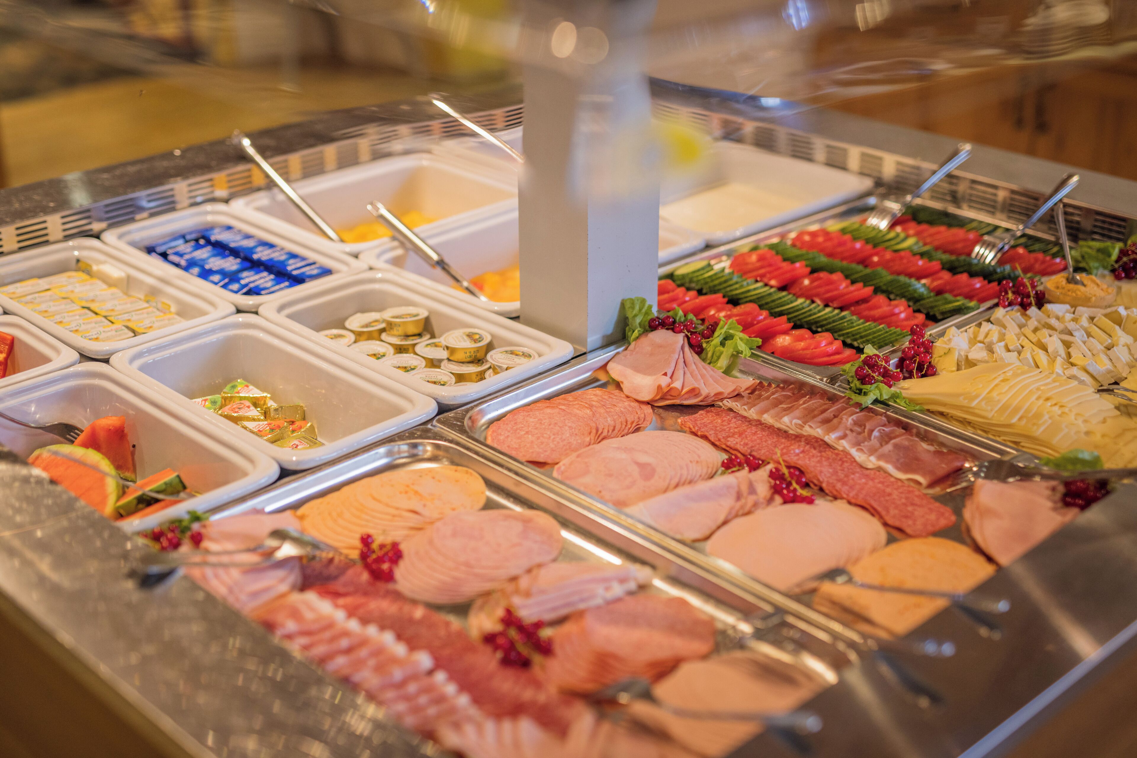 A buffet with various food options including meats, cheeses, and fruits.