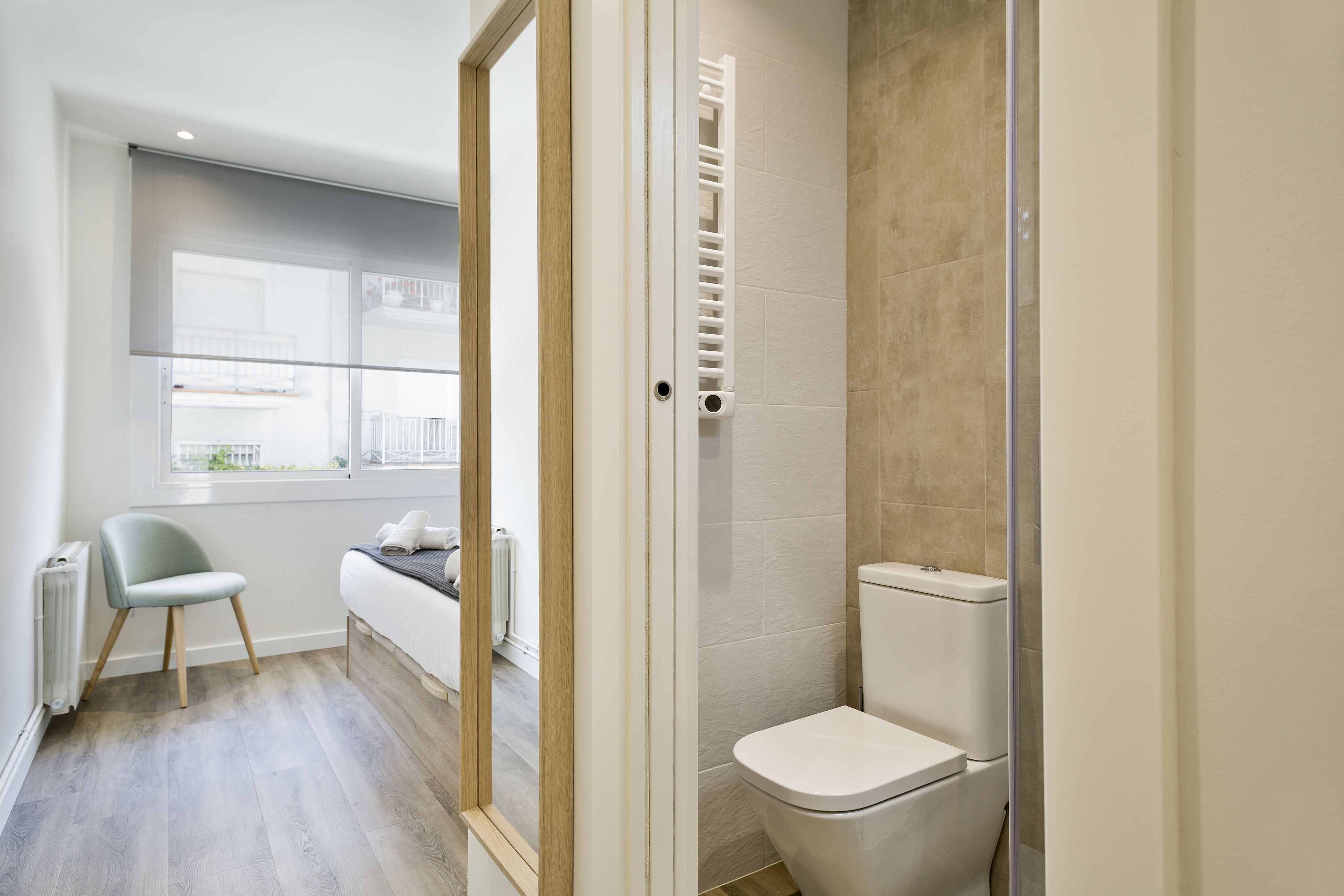 A modern bathroom with a toilet, a shower, and a window.