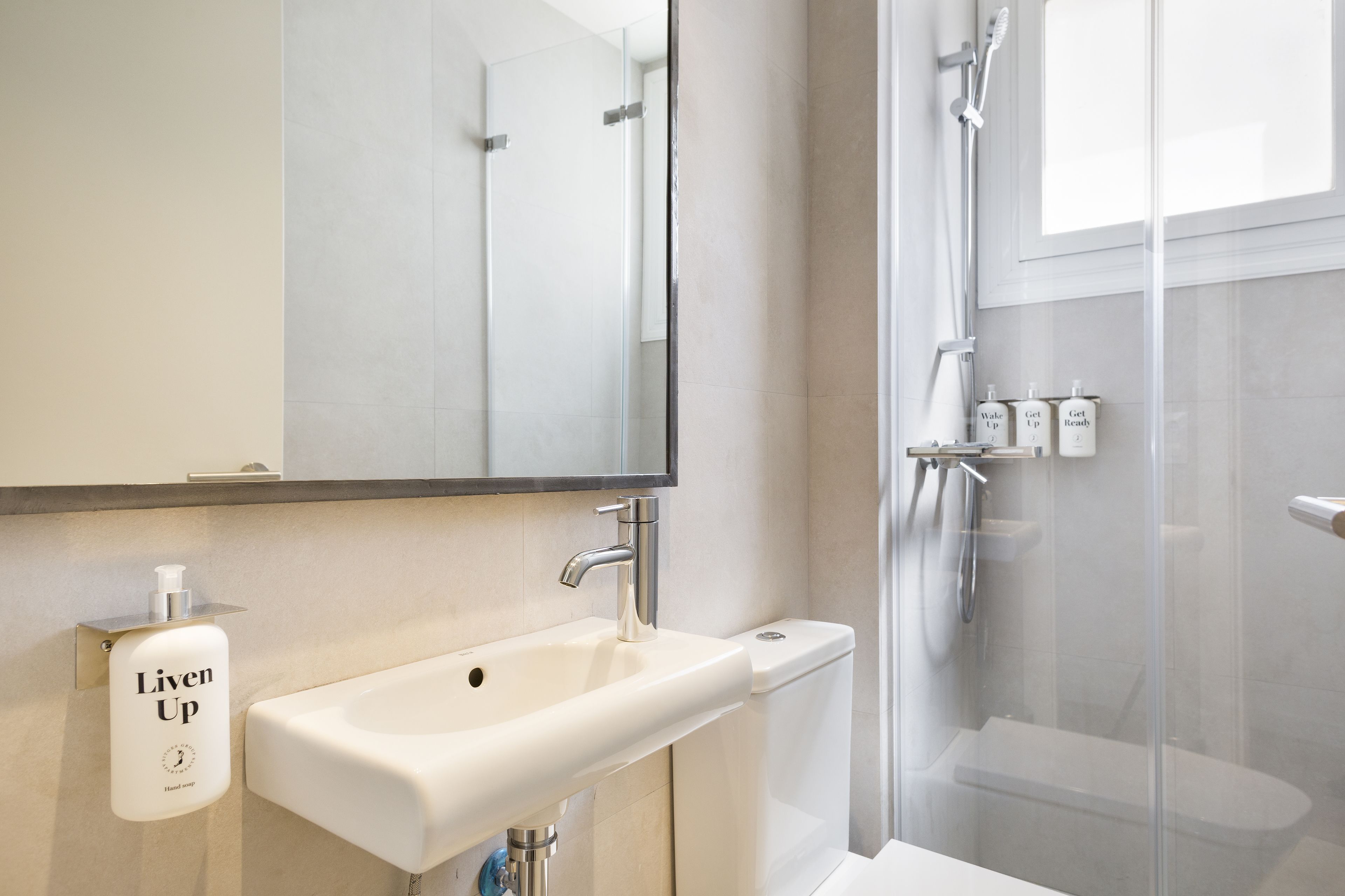 A modern bathroom with a white sink, a mirror, and a glass shower enclosure.