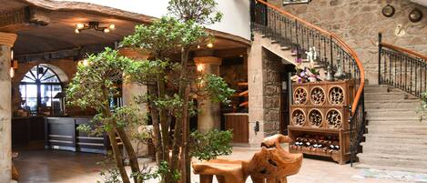 Un hall espacioso con una escalera de madera, un botellero y un árbol central.