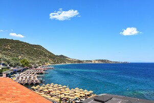 Una zona costera con playa, sombrillas y un muelle.