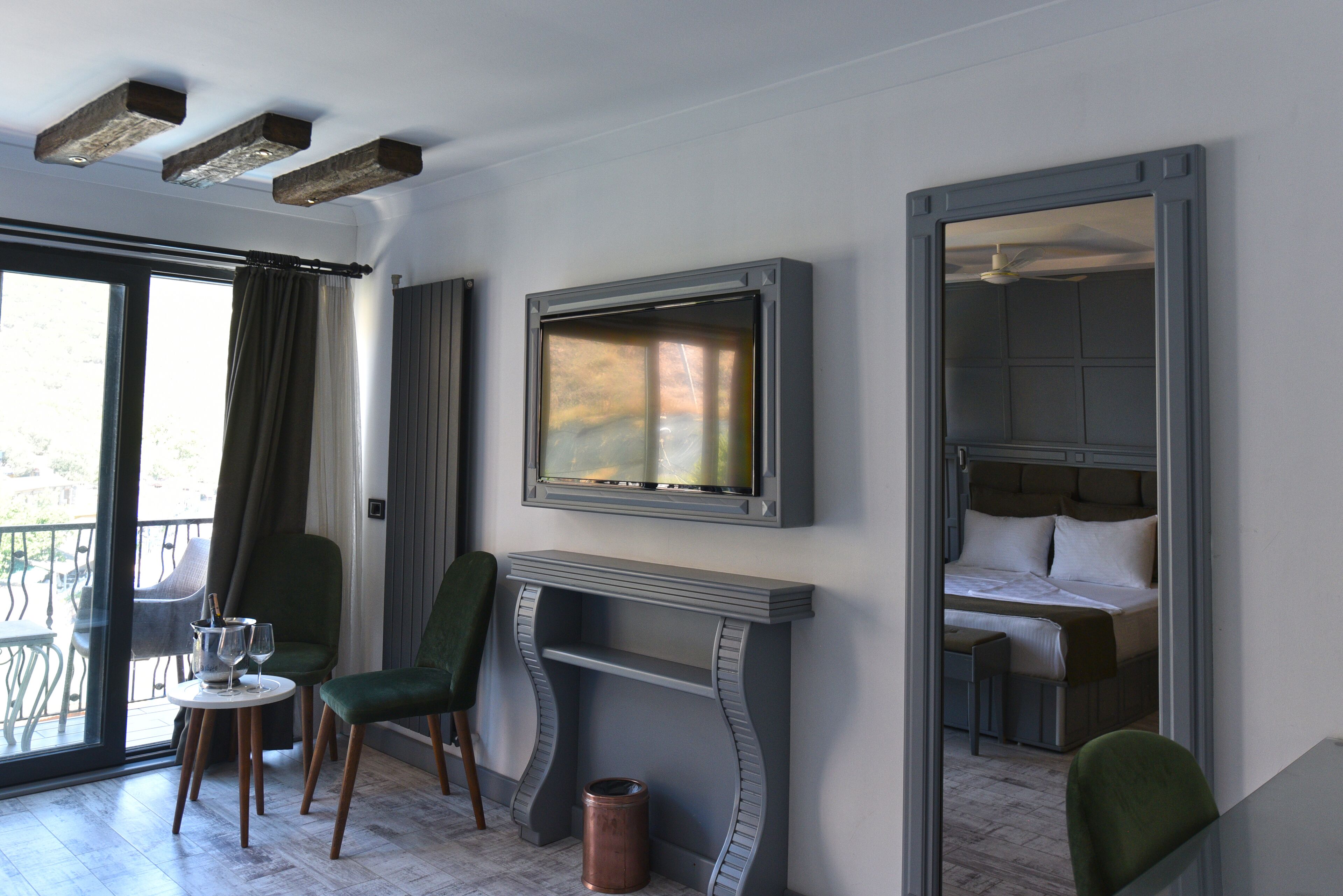 Una habitación de hotel moderna con chimenea, televisor montado en la pared y balcón con mobiliario exterior.
