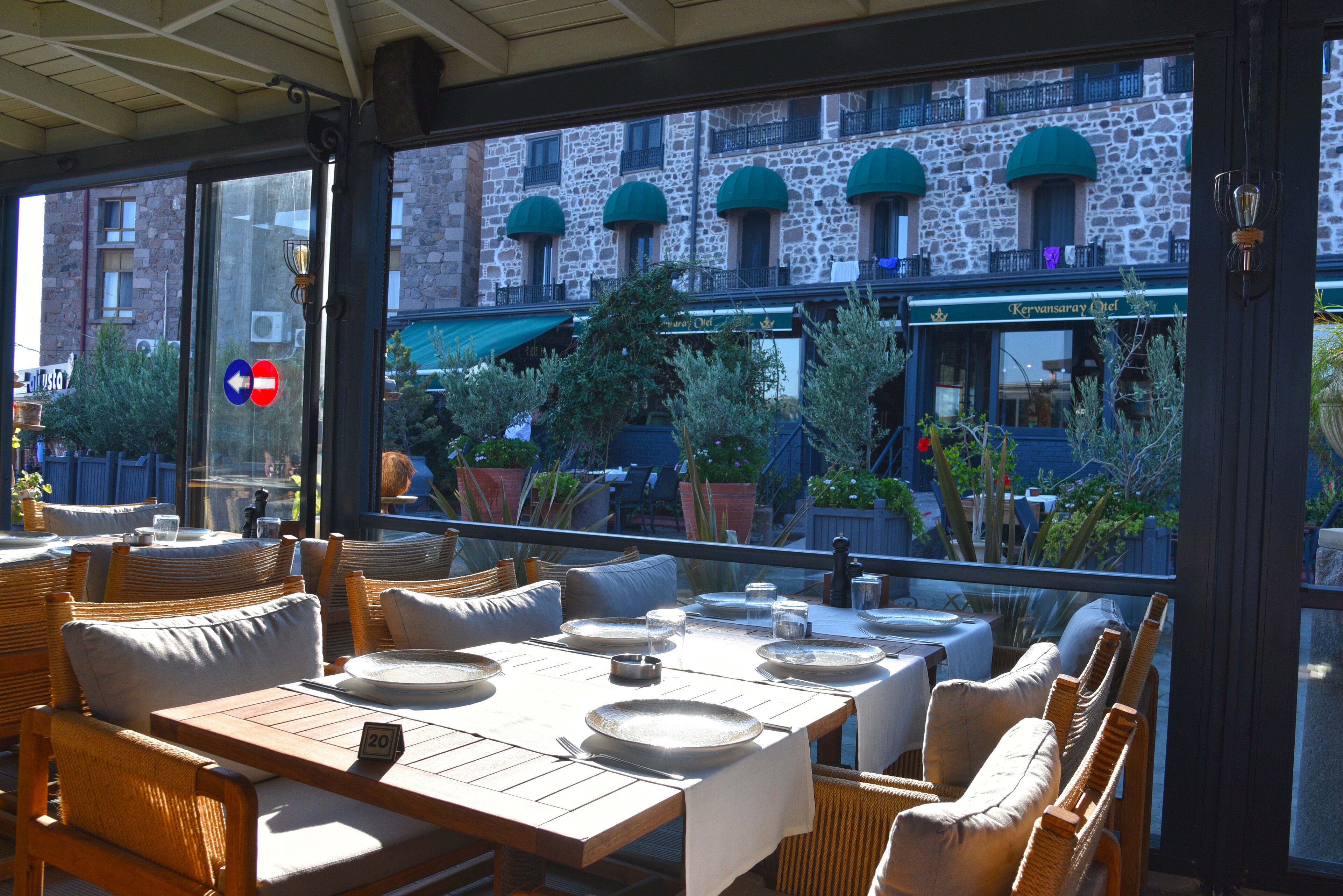 An outdoor dining area with wicker furniture and a view of a stone building with green awnings.