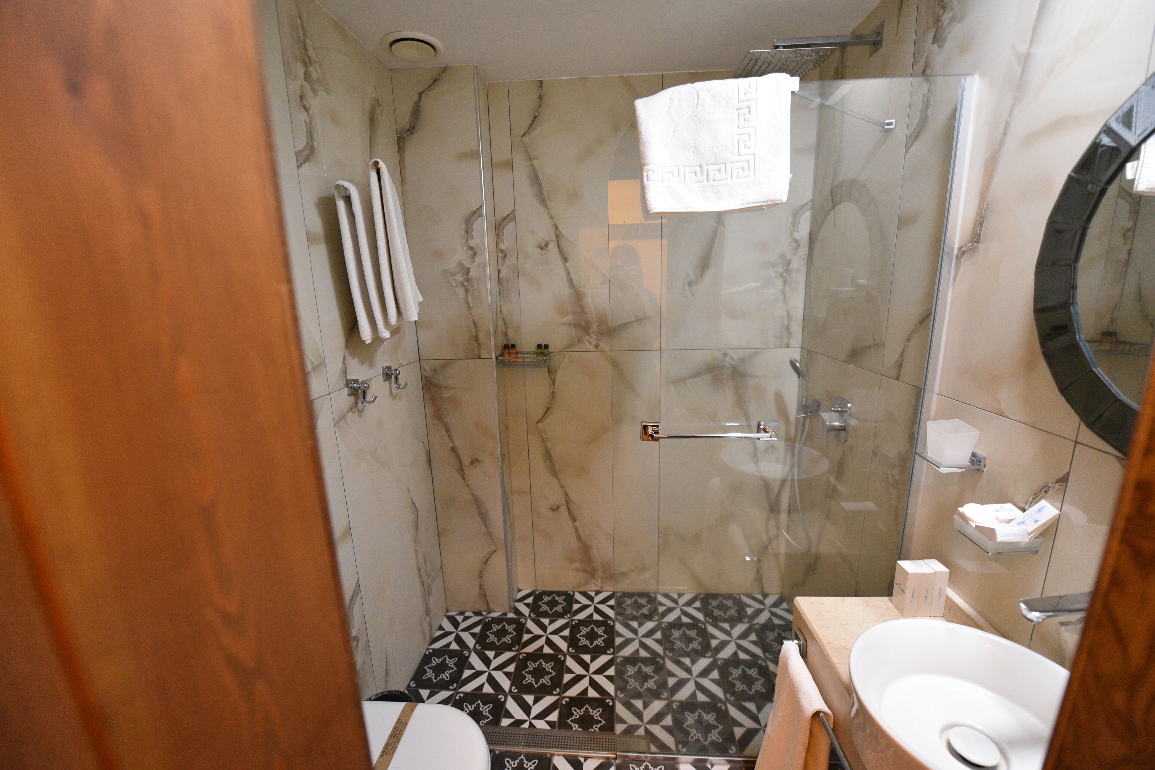 A bathroom with a glass-enclosed shower, a toilet, and a sink.