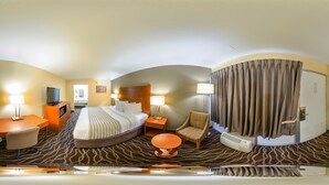 A hotel room with a bed, a desk, a chair, a round table, and a bathroom with a shower curtain. - Econo Lodge Inn & Suites Hardeeville I-95 (Hardeeville)