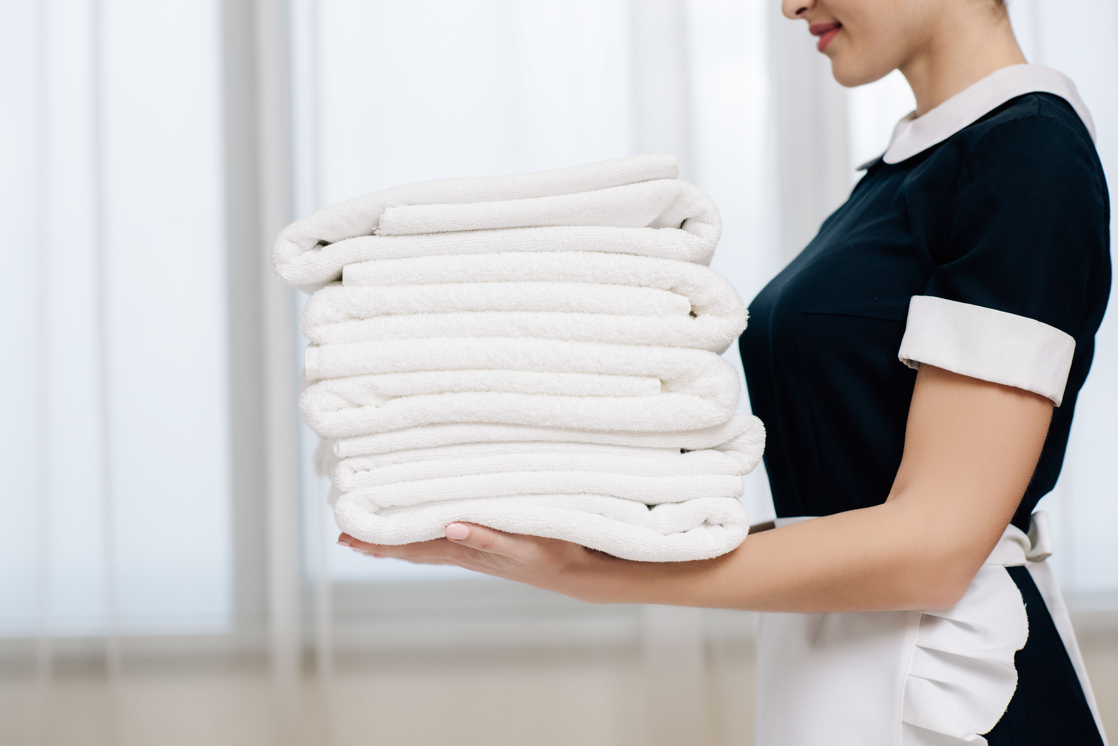 A person holding a stack of white towels.