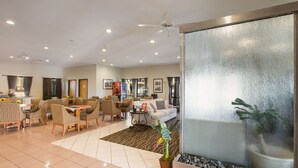 A spacious hotel lobby with a dining area, a sofa, and a large window with a view. - Econo Lodge Inn & Suites Hardeeville I-95 (Hardeeville)