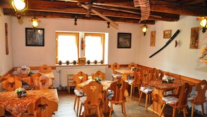 Un comedor con mesas y sillas de madera, un radiador y cuadros en las paredes.