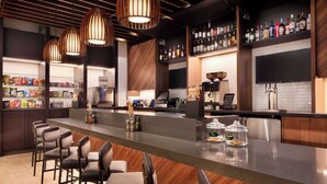 A modern bar area with a long counter, bar stools, and a variety of beverages on shelves. - Hyatt Place Oklahoma City / Bricktown (Oklahoma City)