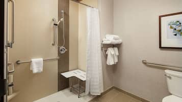 A modern bathroom with a shower, toilet, and a small bench.