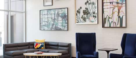 Una sala de estar moderna con un sofá gris, una mesita de centro redonda y dos sillones azules.