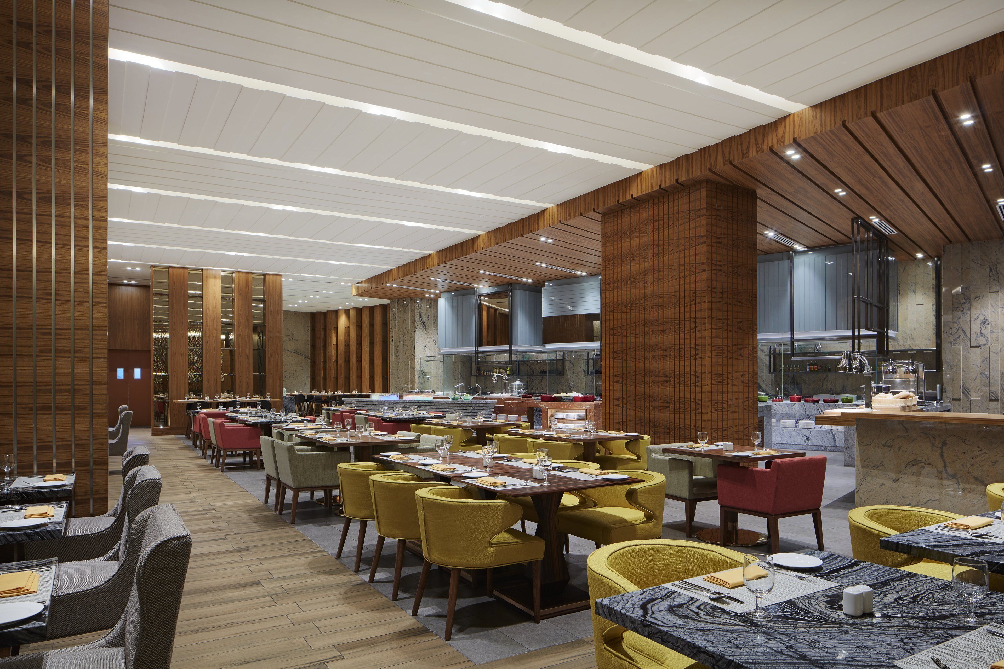 Un restaurante moderno con paneles de madera, varias mesas de comedor y sillas amarillas.
