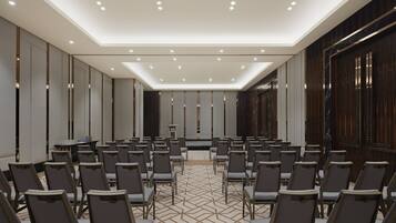Un salón de conferencias con hileras de sillas, un atril y un escenario.