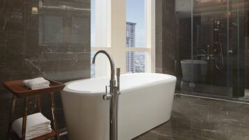 Een moderne badkamer met een vrijstaand bad, een douche met glazen wand en een vloer van marmer.