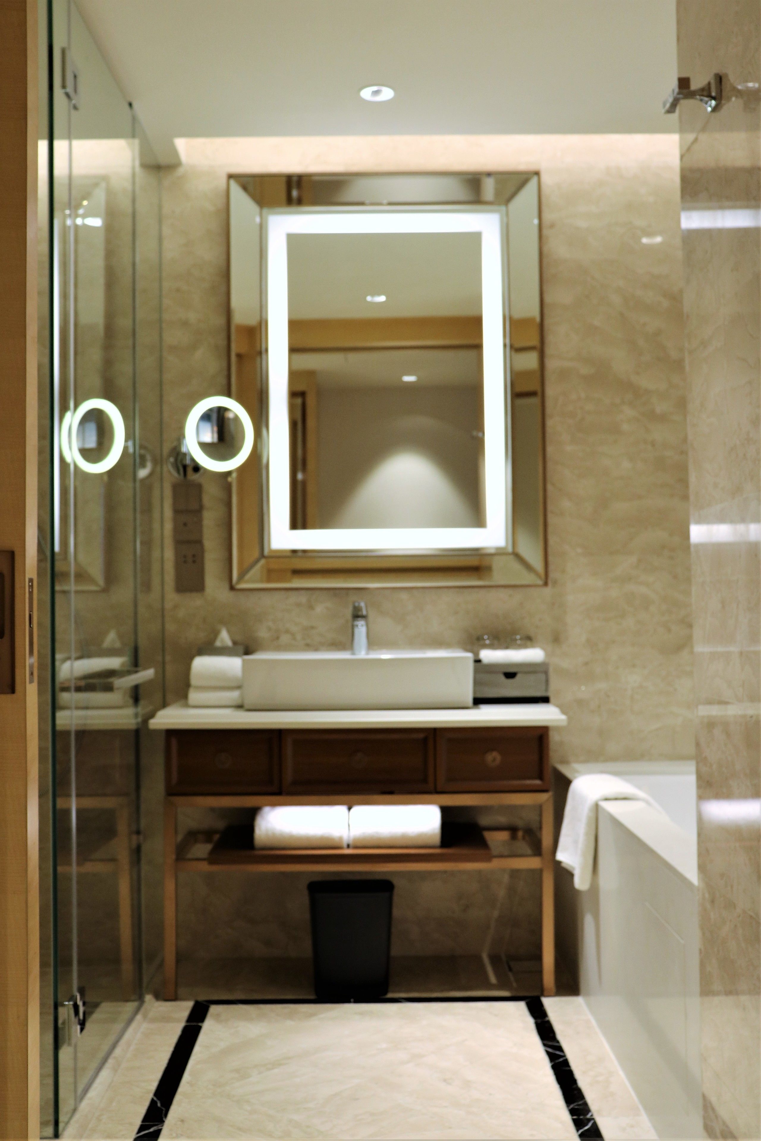 A modern bathroom with a glass shower enclosure, a large mirror, a sink, and a bathtub.