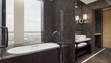 A modern bathroom with a large bathtub, a sink, and a mirror with wall sconces.