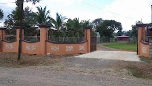 A gated entrance with a concrete pathway leading to a building. - Cabañas San Isidro (La Fortuna)