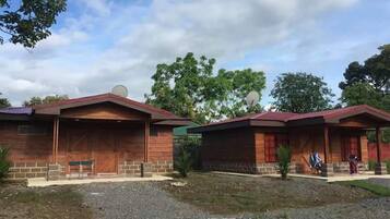 Two wooden cabins with brick foundations, satellite dishes, and a gravel driveway.