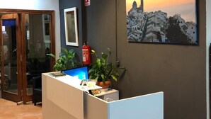 A reception desk with a computer, a fire extinguisher, and a framed picture on the wall. - Fornet (Altea)