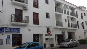 A multi-story building with balconies, a sign for a hostel, and a parked car. - Fornet (Altea)