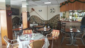A restaurant with tables and chairs, a bar area, and a Christmas decoration. - Fornet (Altea)