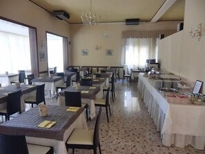 A dining area with multiple tables and chairs, a chandelier, and a buffet setup. - Mayer (Jesolo)