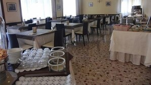 Un espace repas comprenant plusieurs tables, des chaises et un buffet.