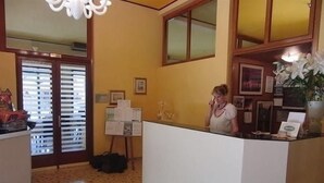 Un espace d’accueil comprenant un comptoir de réception, un panneau d’affichage, une plante et un tapis à motifs.
