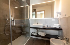A modern bathroom with a glass-enclosed shower, a sink, and a bidet. - Mayer (Jesolo)