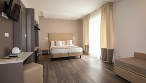 A hotel room with a bed, a desk, a chair, a TV, and a window with curtains. - Mayer (Jesolo)
