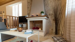 A living room with a fireplace, a sofa, a coffee table, and a TV. - Villa Peonia & Villa Ortansia (Mylopotamos)