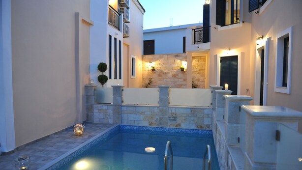 A swimming pool with a stone deck, surrounded by white walls and balconies with black shutters. - Villa Peonia & Villa Ortansia (Mylopotamos)