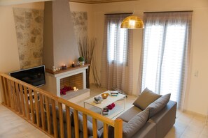 A living room with a fireplace, a sofa, a coffee table, and a TV. - Villa Peonia & Villa Ortansia (Mylopotamos)