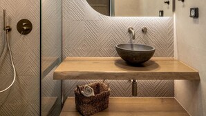 Ein Badezimmer mit einem Holzkosmetikschrank, einem Aufsatzwaschbecken, einer Duschkabine und einer Wand mit Zickzackmuster.