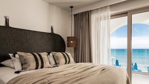 Ein Hotelzimmer mit einem großen Bett, Meerblick und einem Balkon mit Sonnenschirmen.