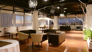 A spacious living area with a high ceiling, wooden flooring, and a seating arrangement including sofas and chairs. - Atlantida Hotel (Río Grande)