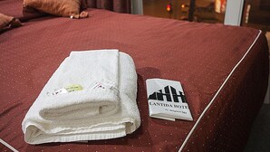 A neatly made bed with a folded white towel and a hotel name tag on the bed. - Atlantida Hotel (Río Grande)