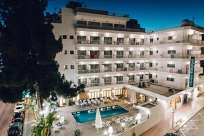 Un hotel de varios pisos con zona de piscina, mobiliario exterior y balcones.