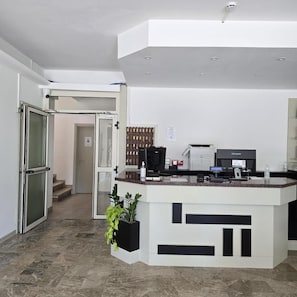 Un área de recepción con mostrador, computadora y máquina de café.