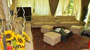 A living room with a beige sofa set, a coffee table, and a floral rug. - Helios (Cervia)