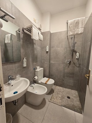 Un baño moderno con ducha, dos lavamanos, inodoro y espejo.