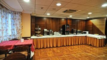 A conference room with a long table, coffee machines, and a buffet setup.